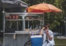 woman in white long sleeve shirt sitting on chair under red umbrella during daytime