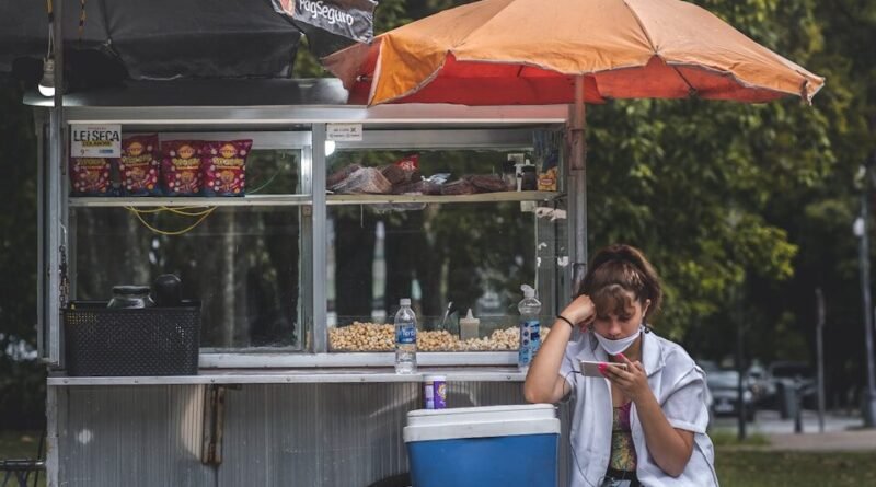 woman in white long sleeve shirt sitting on chair under red umbrella during daytime